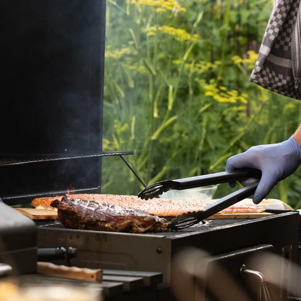 Vlees wordt met een tang gekeerd op de grill