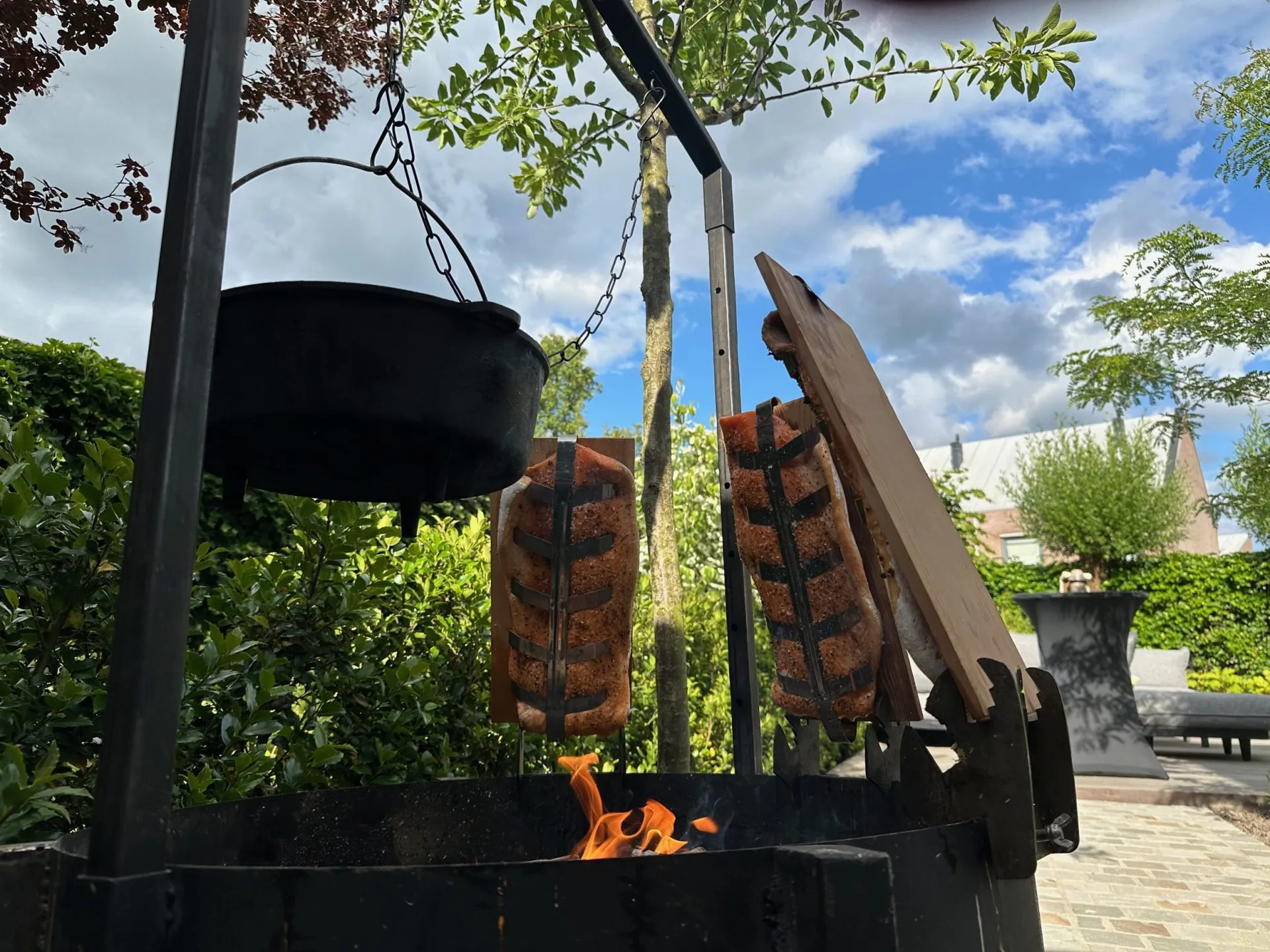 Open vuur met gietijzeren pan en zalm op planken