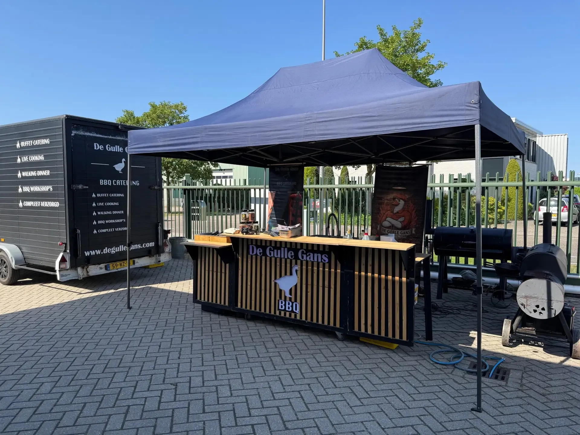 Tent, BBQ-counter en trailer van De Gulle Gans op locatie
