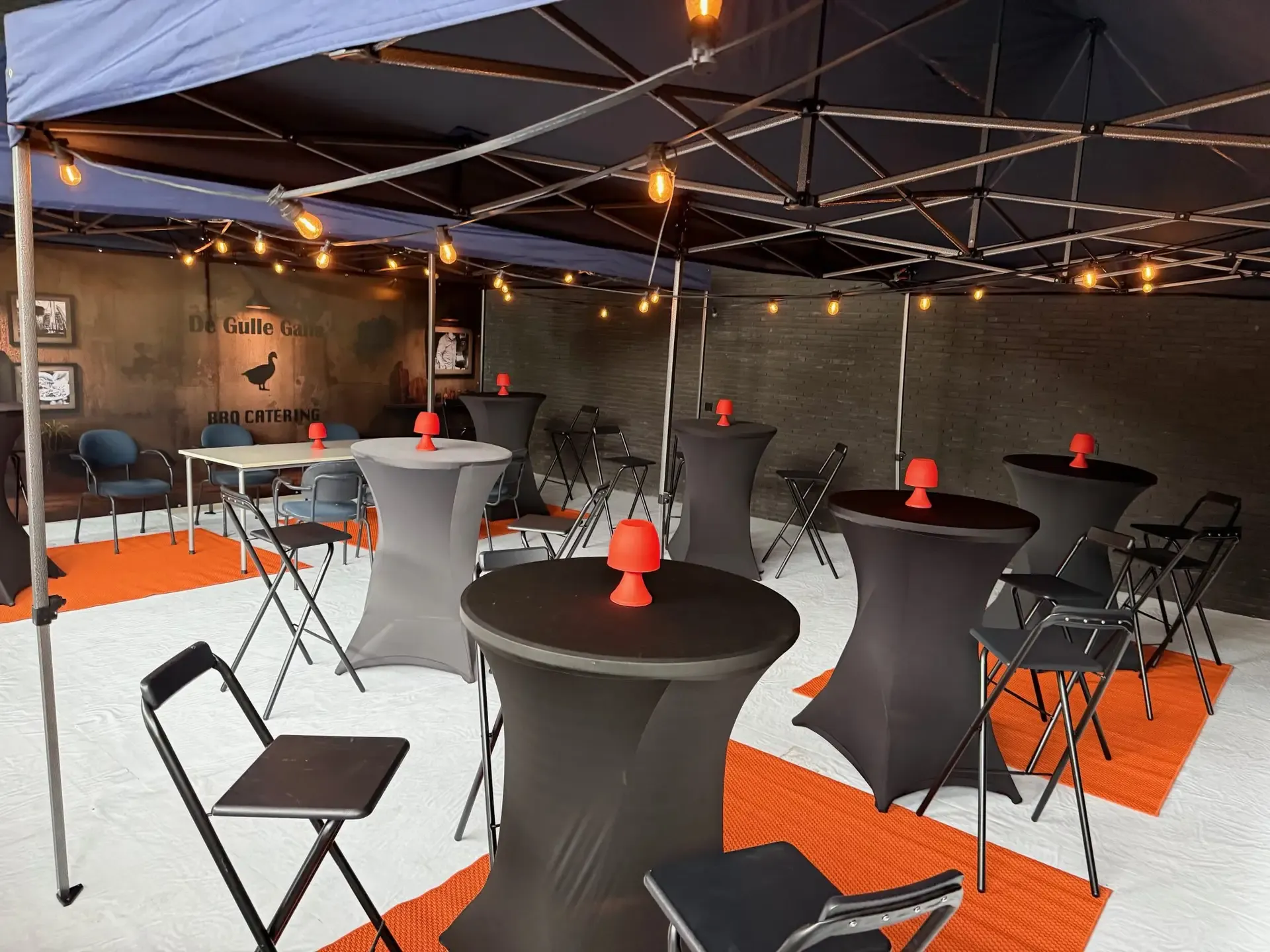 Tent met statafels en verlichting, klaar voor de gasten